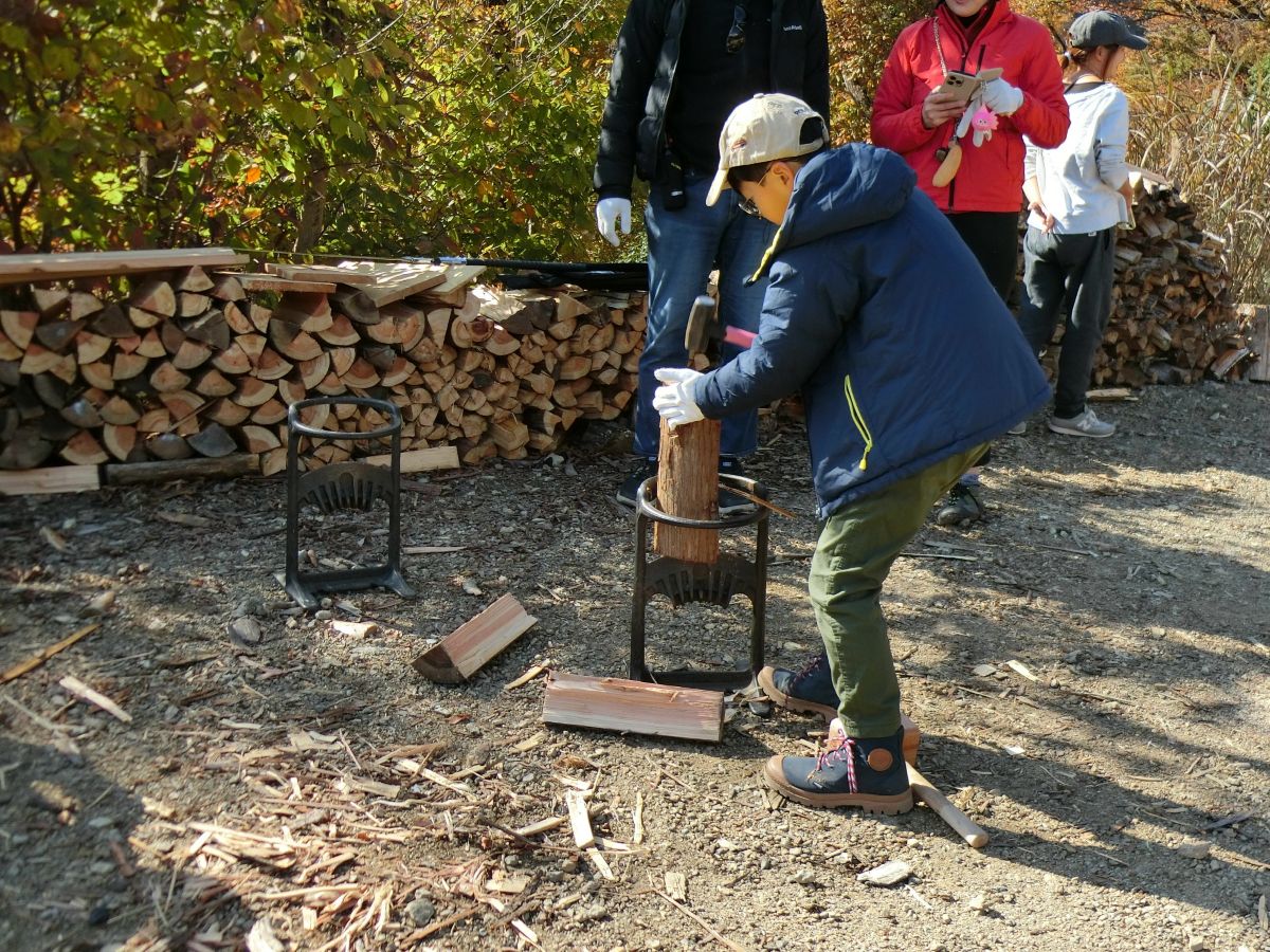 薪割台とハンマーを使って薪を割る参加者