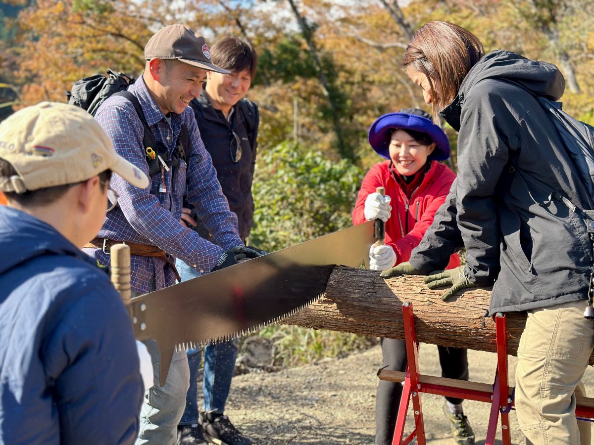 大きなのこぎりを使って親子で丸太切り体験
