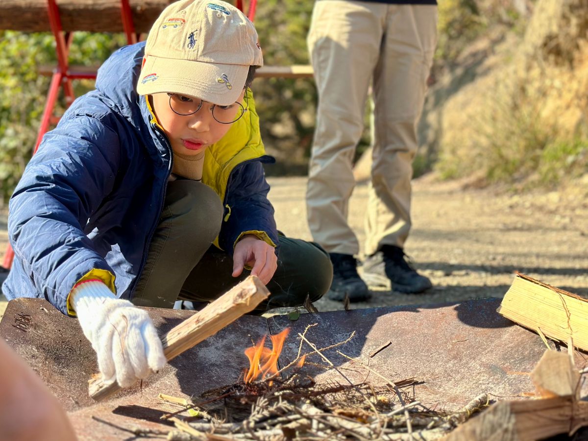 焚火台に木をくべる参加者